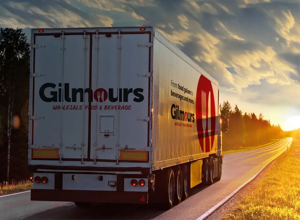 Gilmours wholesale food and beverage truck driving along a country road at sunset