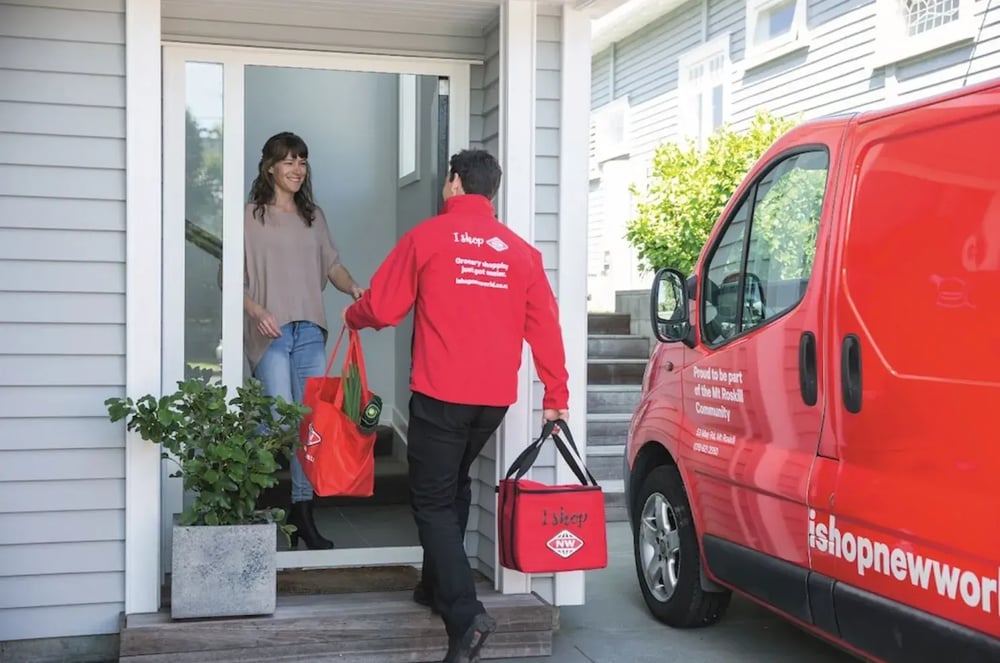 Metro New World driver handing a grocery delivery to a customer at her front door