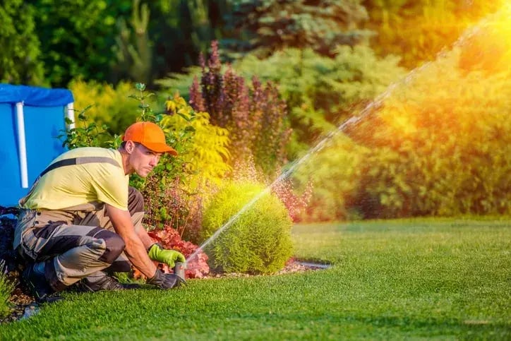 Grounds maintenance worker adjusting a garden sprinkler