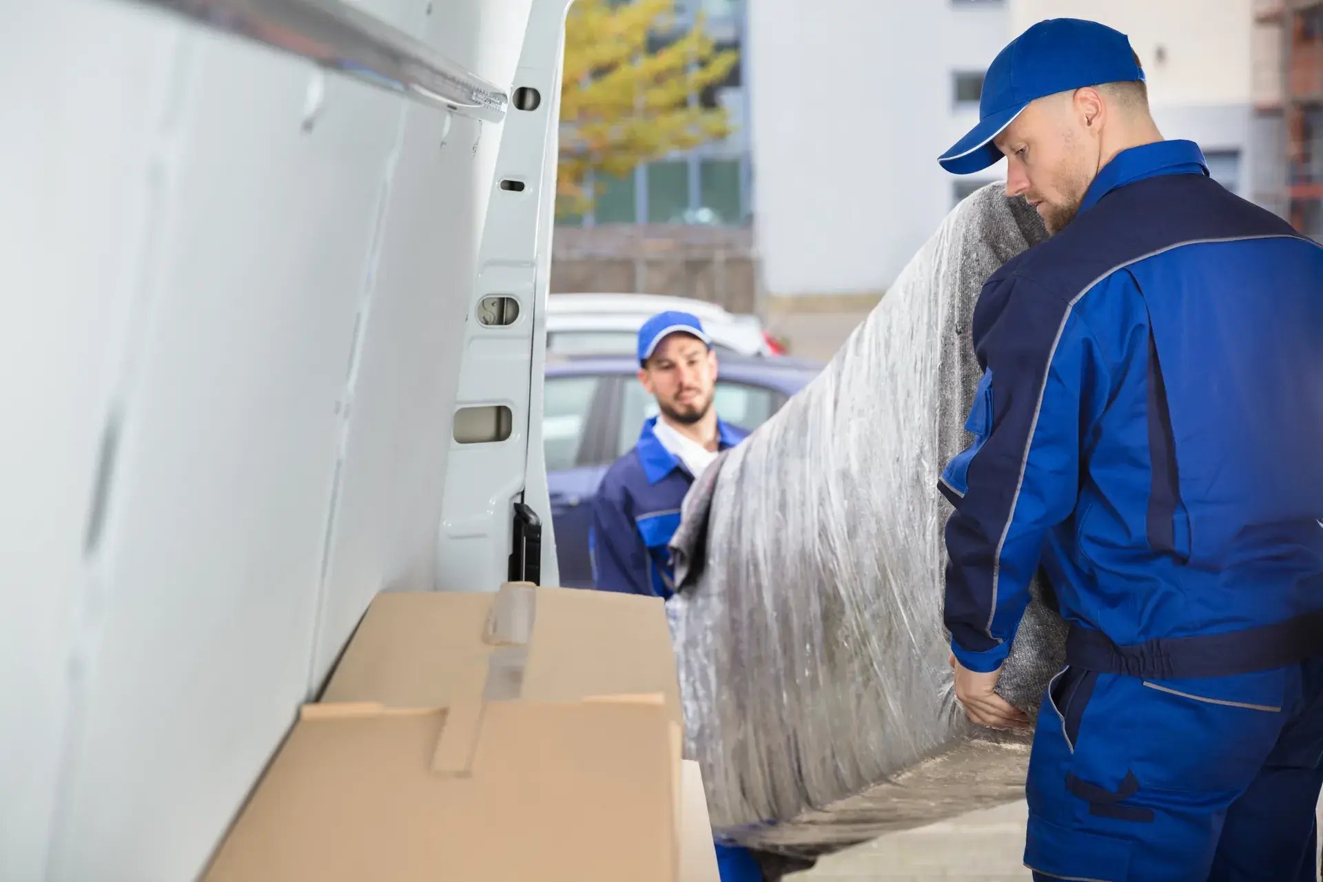 Two delivery workers loading a bulky item into a van