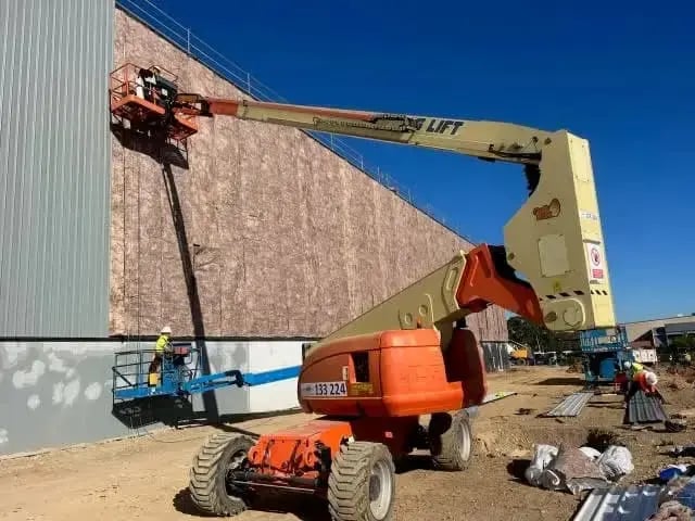 Boom lifts working on the side of a large commercial building under construction